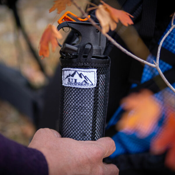 A hiker holds the ULA Deploy Bear Spray Holder in his hand