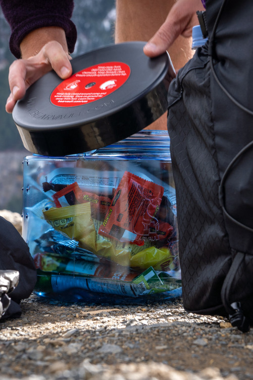 A BearVault being opened by a hiker. The BearVault also keeps your snacks from getting crushed.