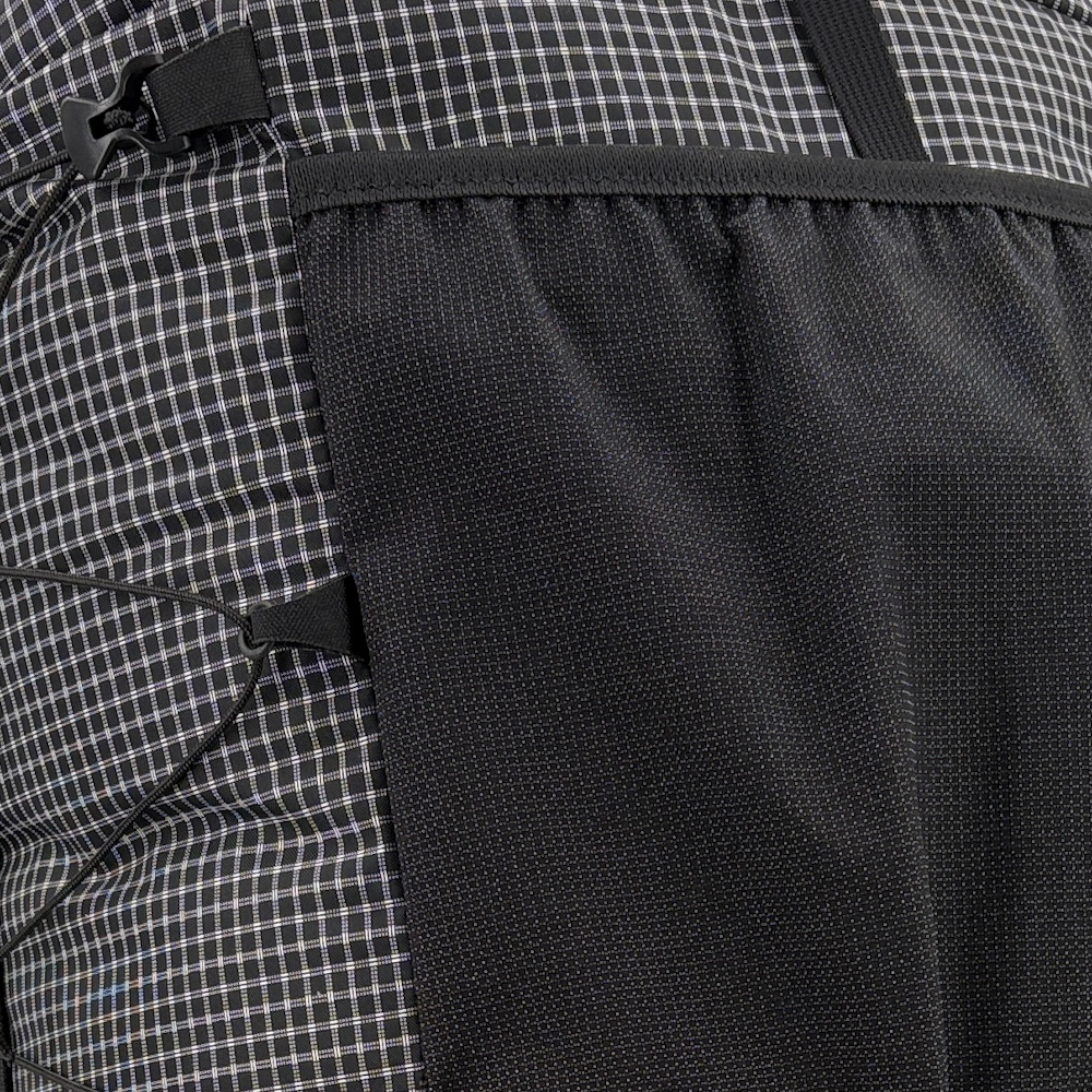 Backpacker on the trail with a ULA 2024 Catalyst attaching his bear canister to the top of his pack with a Y-strap