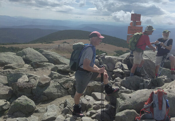 A group of day hikers gather at a summit.