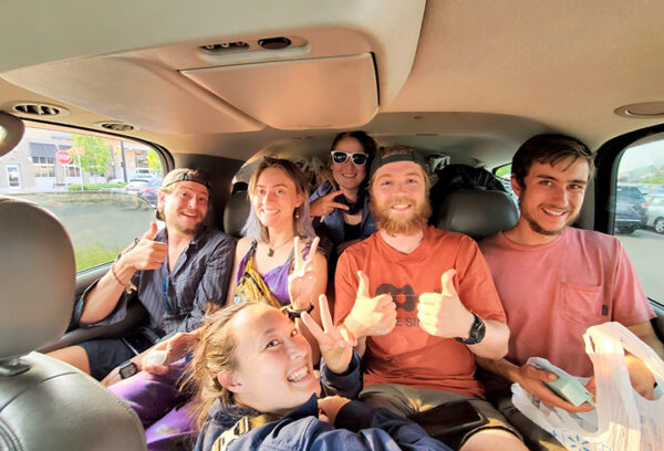 A group of people in a van smile.