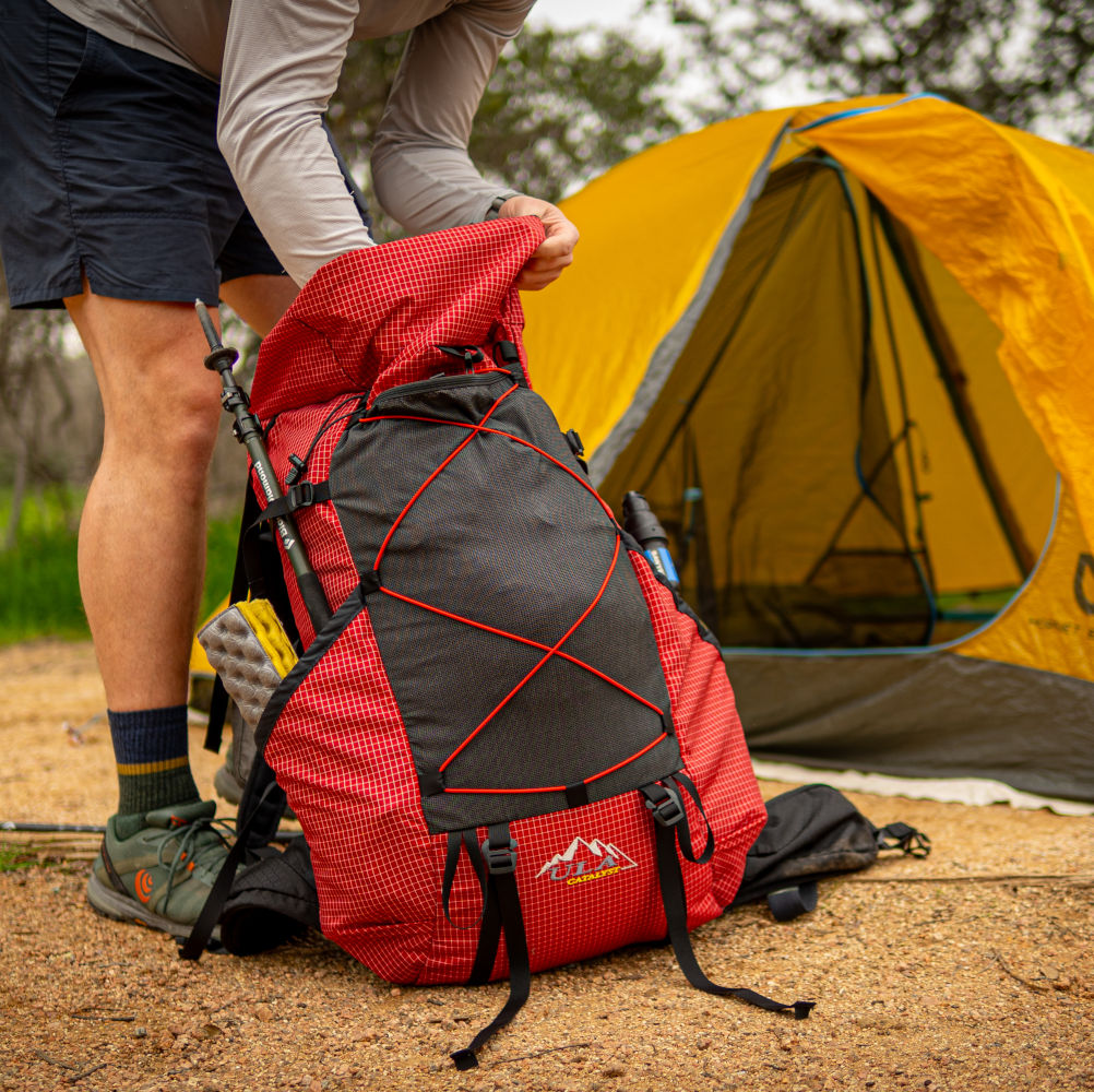 Backpacker setting up camp with his red Catalyst backpack in the foreground