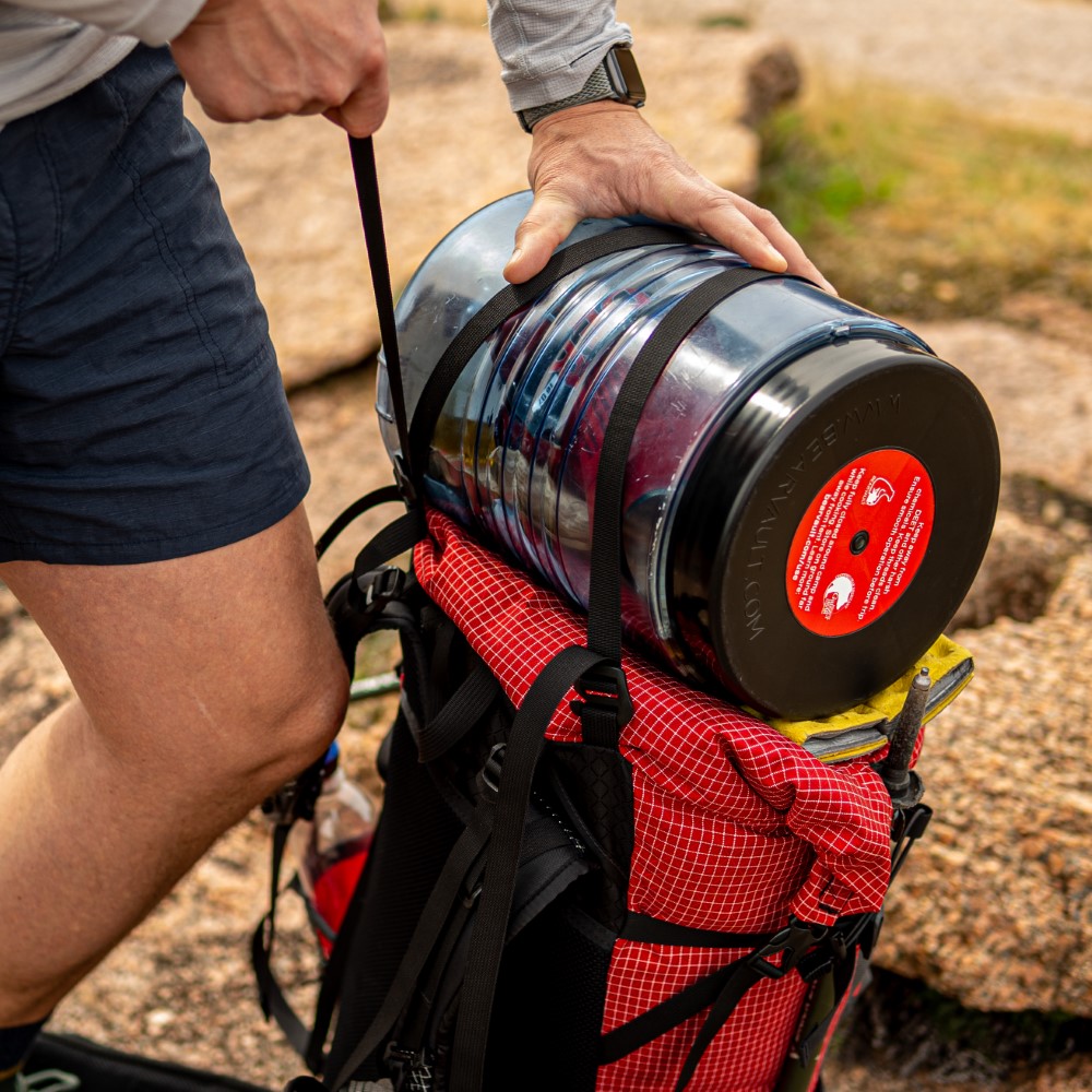 Backpacker tightens top y-strap of Circuit over bear canister