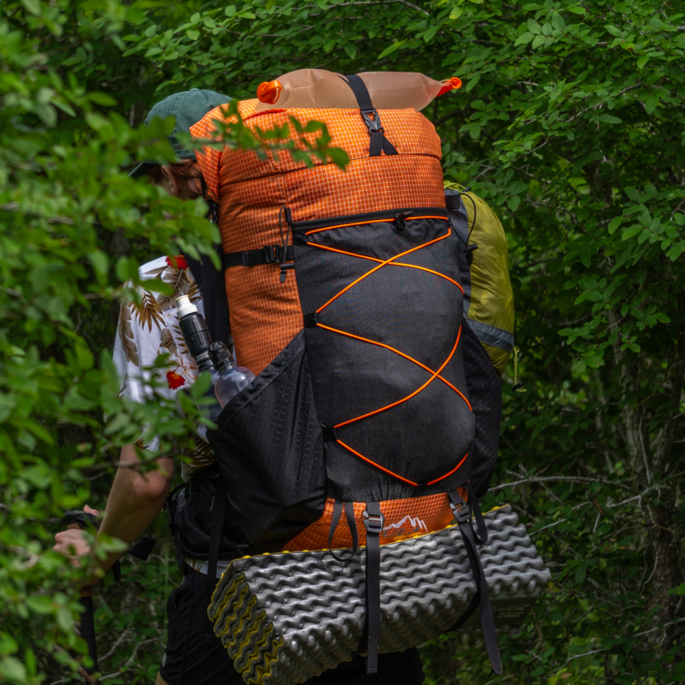 Backpacker on the trail with a ULA Circuit with Bottom Straps carrying a sleeping pad
