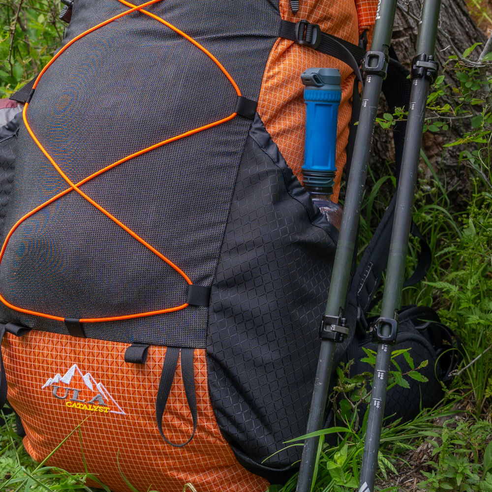 Backpacker clipping top compression straps of a red Catalyst backpack