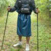 A backpacker is a teal colored ULA Rain Kilt. He is hiking in the rain.