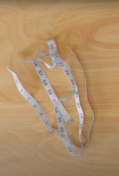 A measuring tape sits on a wooden table top
