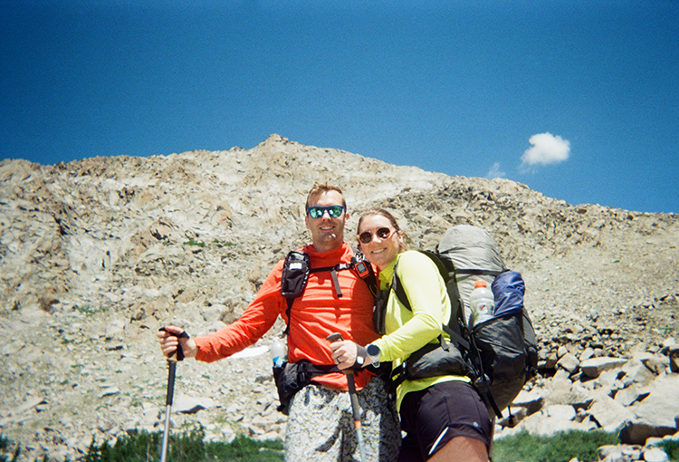 Backpacker reaches for his bear spray from the ULA Deploy Bear Canister Holder on his shoulder strap.