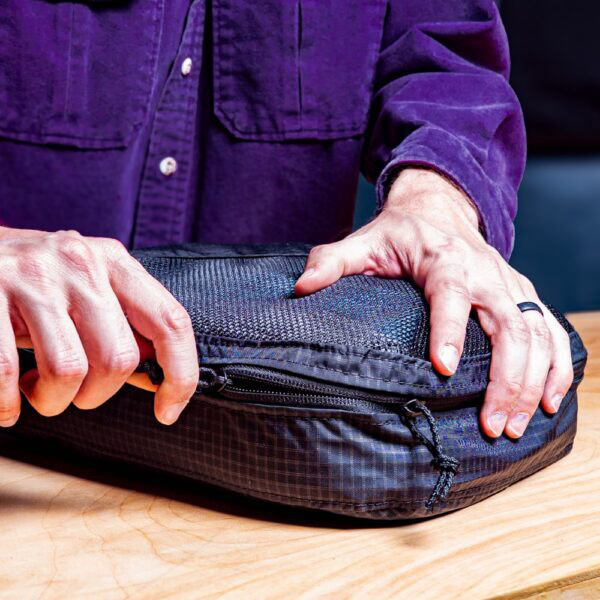 Traveler zips up his packing cube.