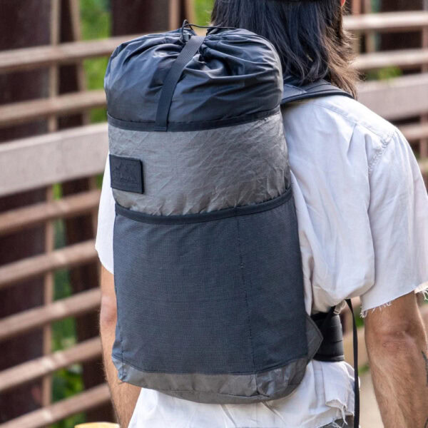 Dayhiker wearing Ultra Packrat while crossing bridge in urban landscape