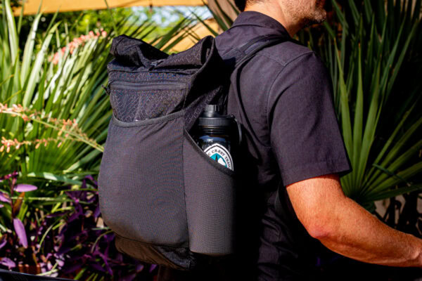 An urban explorer and thru-hiker carries a ULA Node in town, his side water bottle pocket has a water bottle with a PCT sticker on it.