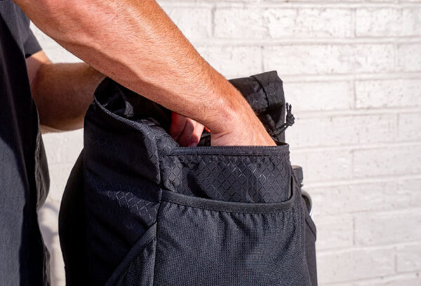A man looks in the zippered pocket of a ULA Black Diamond Robic Node looking for something.