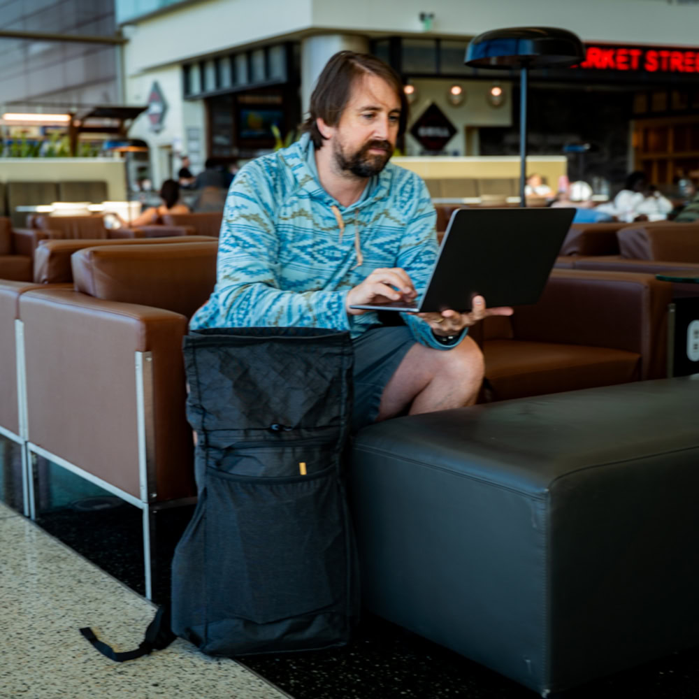 Ultra Node in airport Urban traveler works on laptop in airport, with the ULA Ultra Node open next to him