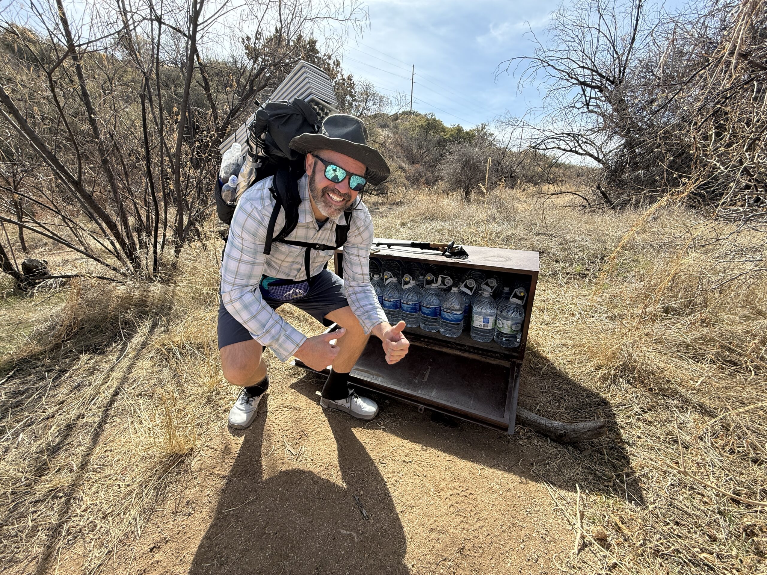 Arizona Trail Water Cache A man smiles next to a water cache.