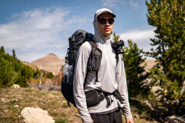 A man wears a backpack and sunglasses in Montana.