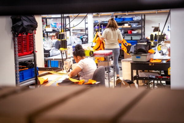 Two ULA team members build orange robic backpacks in our shop in Logan, Utah.