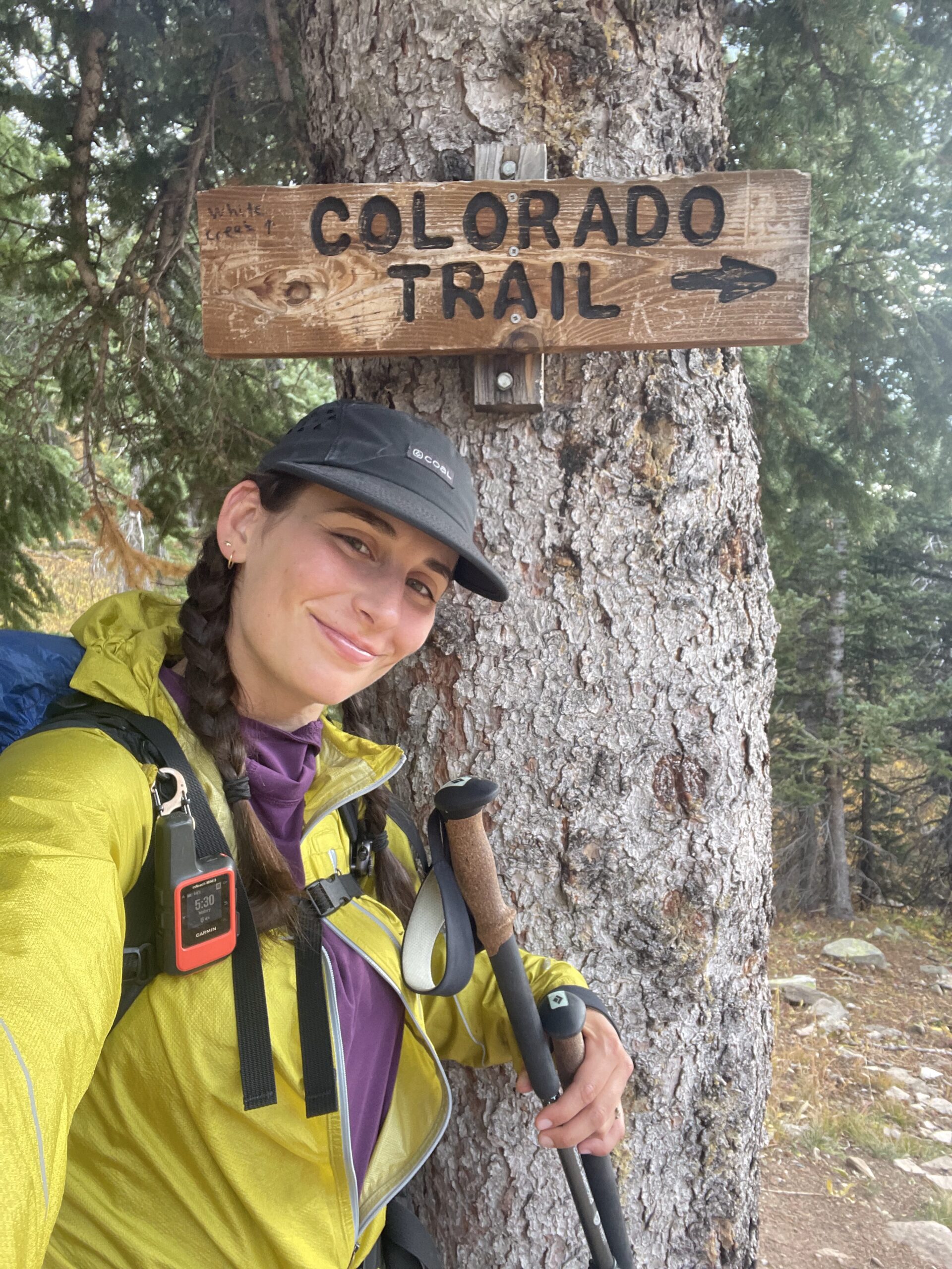 Baja on the CT A woman poses next to a wooden sign on the Colorado Trail
