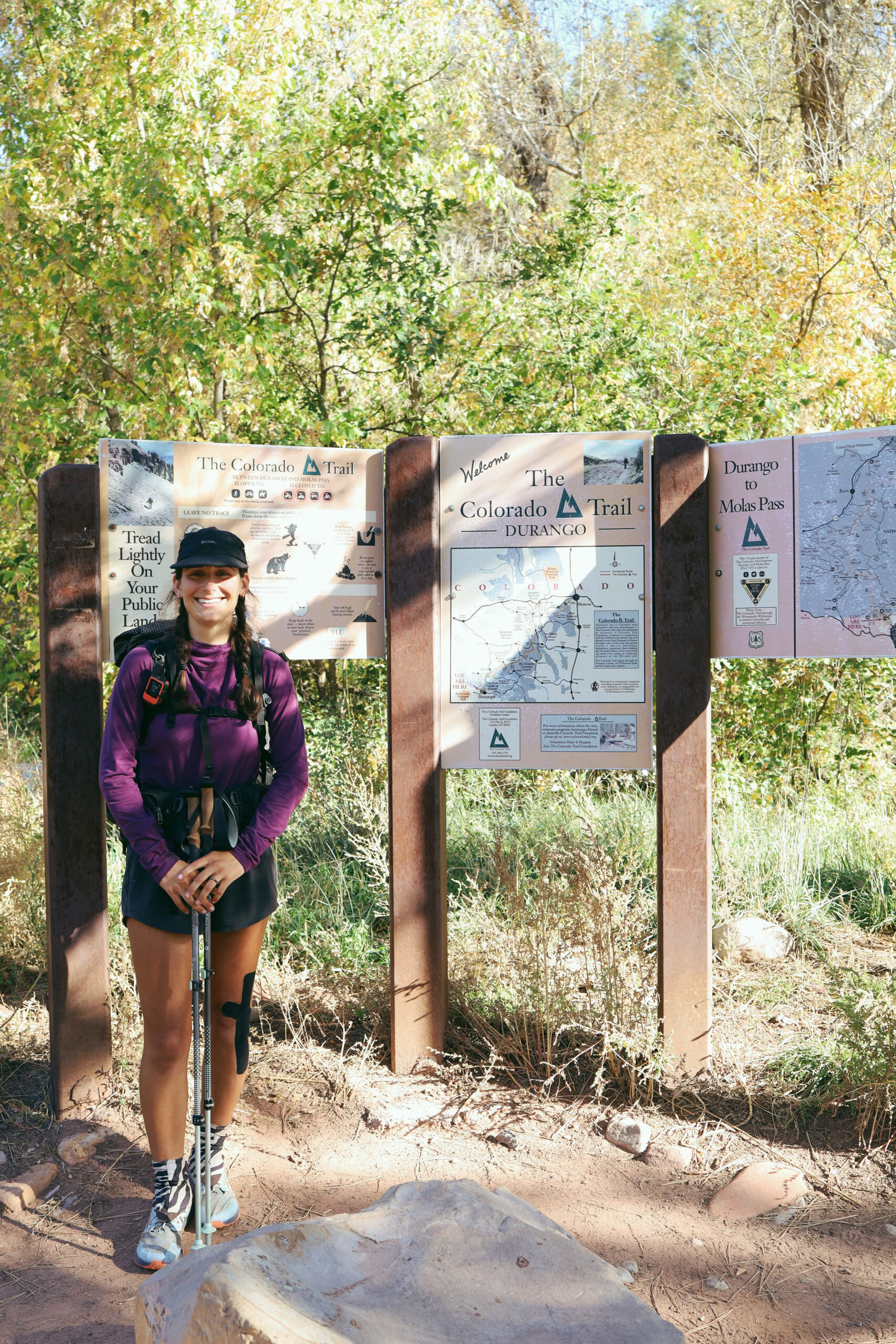 Baja on the CT A woman poses next to a trail information board