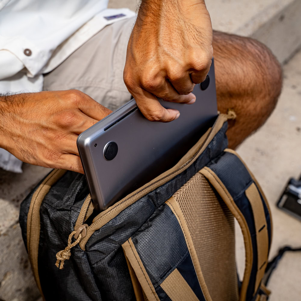 A man pulls his laptoip from the ULTRA Muse Backpack
