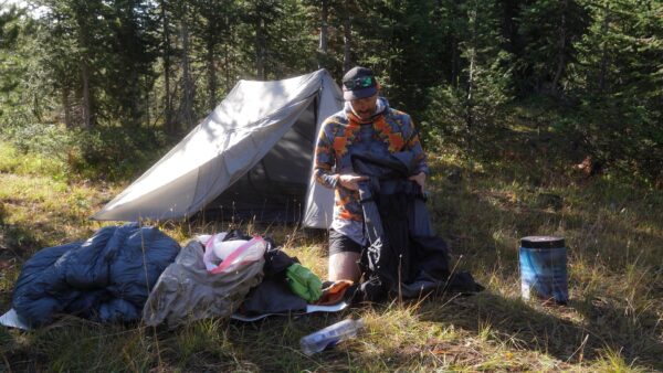 A man loads his backpack while out on a camping trip.