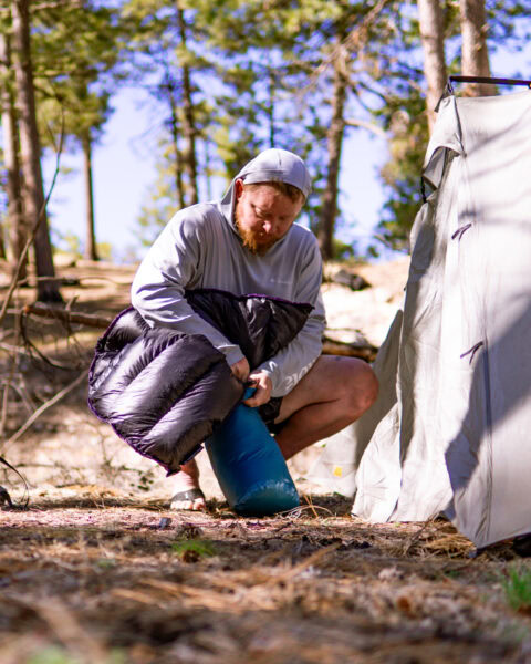 A man packs away his sleeping quilt.