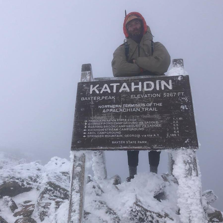 Garrett on Katahdin A man stands at the Katahdin Sign