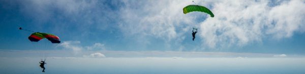 Two sky divers float in a blue sky